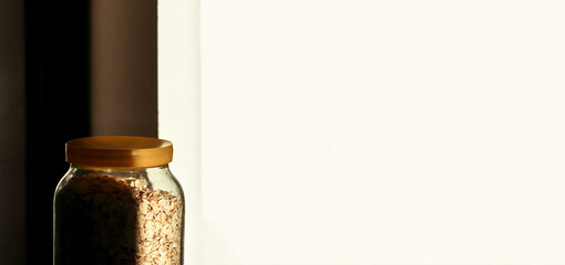A minimalistic scene featuring a jar of oatmeal against a clean white background, with subtle...