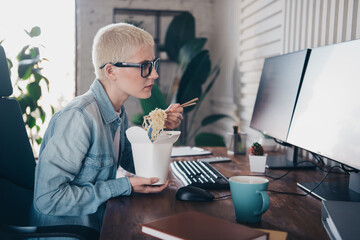 Young professional enjoying noodles while working remotely from home office