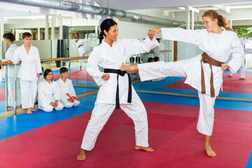 Young girl fighting with her karate teacher during group karate training. Other kids watching their moves. © JackF