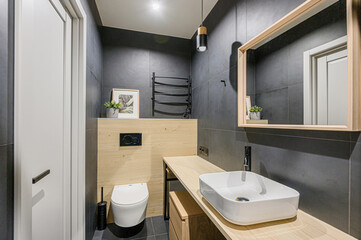 Modern bathroom with gray tile, light wood accents, and a sleek, minimalist design. Bright and stylish.