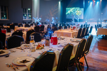 Elegant banquet hall with decorated tables, festive lighting, and VU 20 anniversary stage setup...