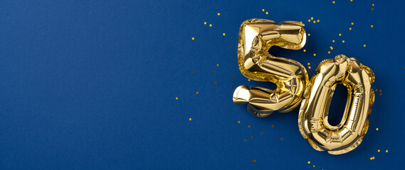 Gold number balloons shaped as fifty, symbolizing celebration, displayed with confetti on blue