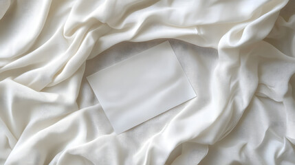 A blank card resting on luxurious white fabric, creating an elegant and serene composition.