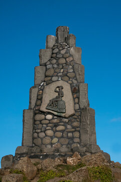 Stone monument with statue of seated figure looking out.