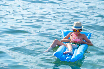 happy child basking in stylish hat and sunglasses enjoys luxurious beach day, young boy leisurely...