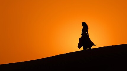 Artistic silhouette of an Indian woman against a glowing orange sunset on a sand dune.