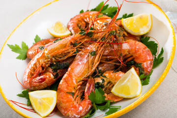 Appetizing grilled shrimps served with parsley and lemon on white plate..