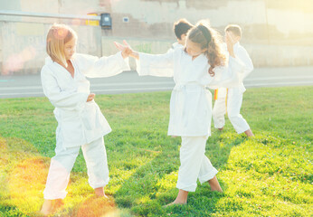 Young female children are trying in sparring to use new moves at karate class