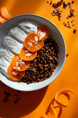 Granola with yogurt, fruits, chia seeds and nuts in a bowl. Chocolate granola with tangerine and yogurt, top view
