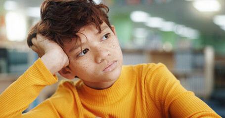 Thinking, child and student in library for education planning, ideas and study of learning solution. Bored, boy and lazy kid with thoughts for curriculum decision, problem solving and exam reflection