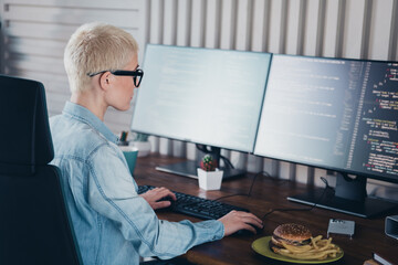 Young female programmer working in a home office setting with casual style