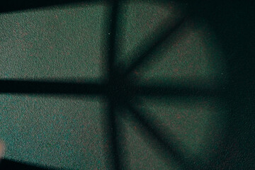Soft window shadows on textured dark green wall