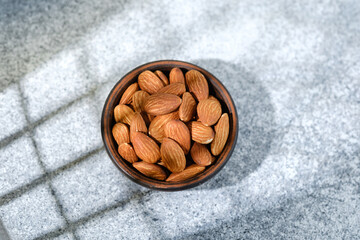 Bowl of whole almonds on light speckled stone background
