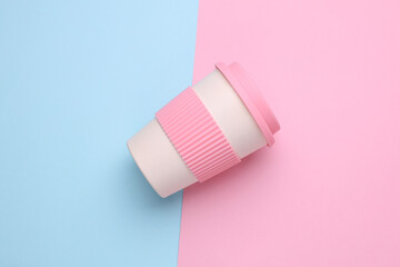 Reusable eco plastic cup for hot drinks on blue pink background. Top view