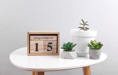 Wooden calendar organizer with date September 15 and decorative plants on table