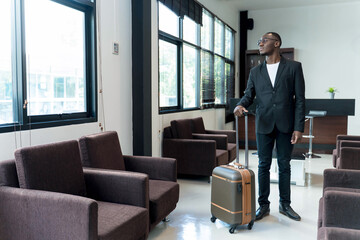 Confident businessman standing with suitcase in airport lounge, looking forward to his journey, ready for business travel or international trip