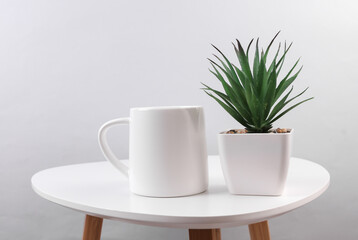 White ceramic cup with decorative plant in pot on table. Mockup for design