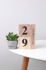 Wooden calendar organizer with date november 29 and decorative plant on table