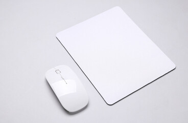 Mockup of white blank computer mouse pad or mat with wireless mouse on gray background