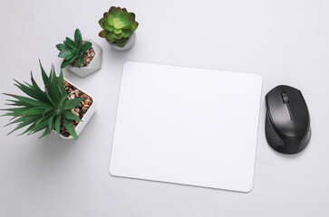Mockup of white blank computer mouse pad with props, decorative plants on gray background. Top...