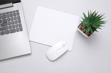 Mockup of white blank computer mouse pad or mat with props, mouse and laptop on gray background. Top view. Flat lay © splitov27
