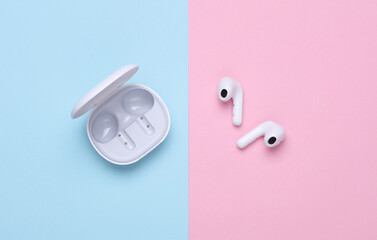 Wireless earphones with charging case on blue pink background
