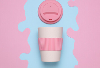 Reusable eco plastic cup for hot drinks on blue pink background