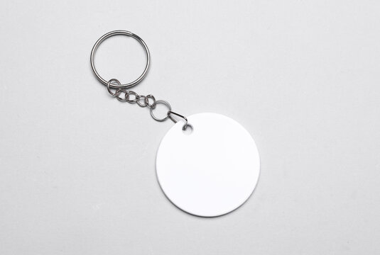 White round plastic keychain on a chain on gray background. Mockup for design