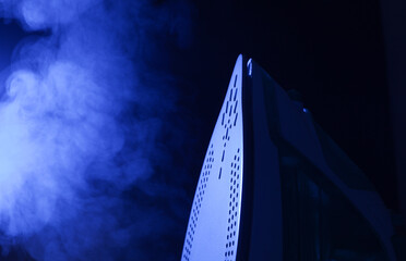 Steam from an iron in blue light on a black background