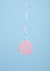 Round pink price tag on rope, blue pastel background