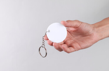 Hand holding white round plastic keychain on chain