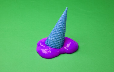 Waffle cone with purple slime on green background. Minimal halloween layout