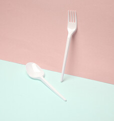 Plastic fork and spoon on a blue pink background. Creative layout