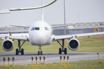 Naklejka premium White passenger airplane taxiing on runway at airport