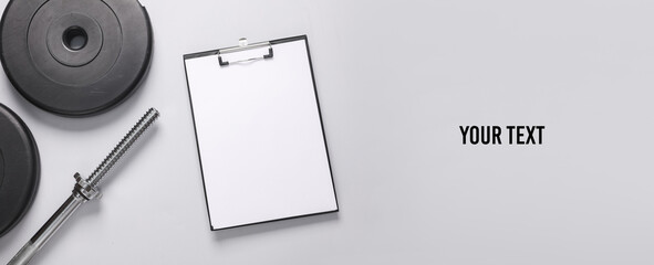 Training program. Clipboard with blank white sheet and barbell disks on gray background. Copy space...