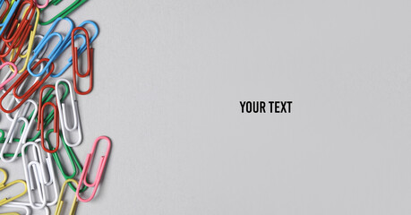 Colored paper clips on gray background. Copy space. Copy space for your text and information