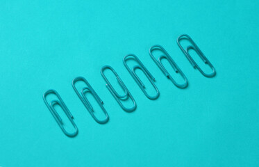 Blue paper clips on blue background. Creative layout
