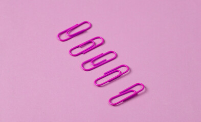 Pink paper clips on pink background. Creative layout