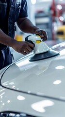 Professional auto body technician carefully polishing silver car surface with high-precision orbital sander in modern automotive repair workshop