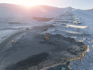 Open pit coal mine in winter landscape with excavator and trucks