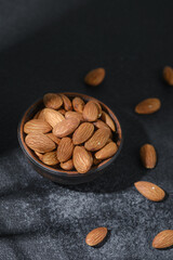 Bowl of almonds on dark textured background healthy snack concept