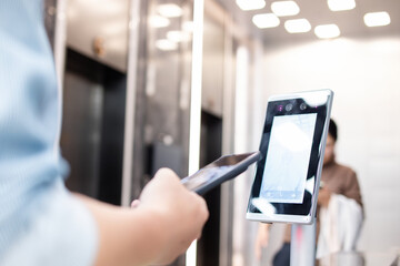 An Asian business man passes through the access control turnstile of the office building by facial recognition