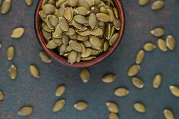 Wooden bowl of pumpkin seeds on green brown background healthy snack