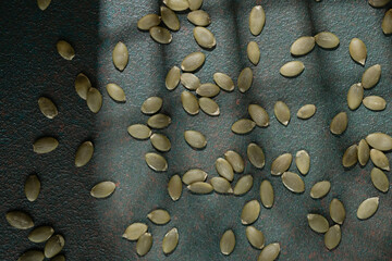Scattered pumpkin seeds on textured green background flatlay concept