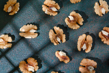 Shelled walnuts scattered on dark textured green background