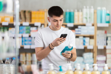 Young man in pharmacy scans QR code mouthwash product, checks certificate on manufacturers website....