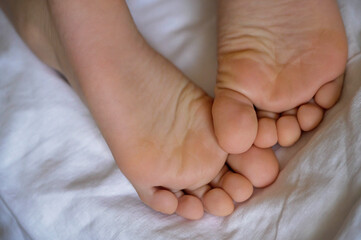 Children's feet and heels on a white bed. Sleep mode babies 6 y.o.