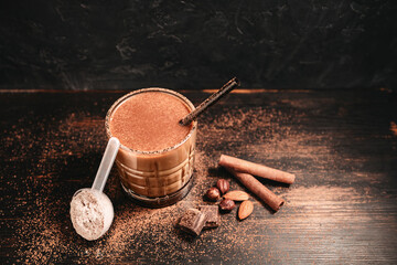 Healthy protein milkshake in a glass with a straw, a measuring scoop of whey protein powder,...