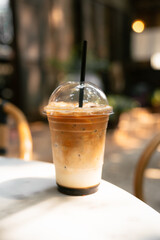 Iced Latte in Takeaway Cup on Outdoor Cafe Table with Warm Natural Light