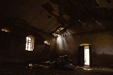 Abandoned interior of a dilapidated church building with shafts of light illuminating debris and...